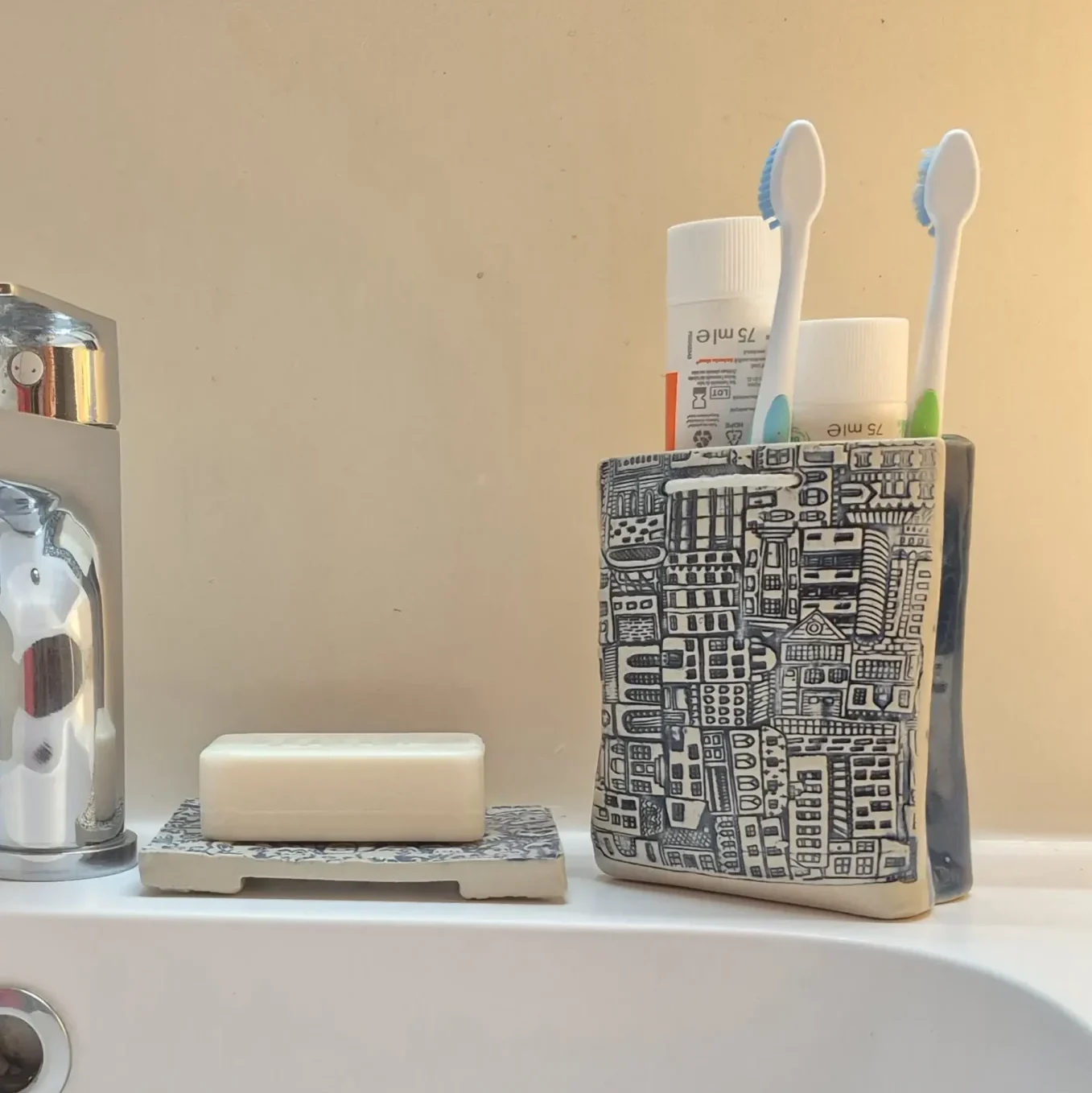 Pot de rangement en céramique motif ville avec brosses à dents dans une salle de bain