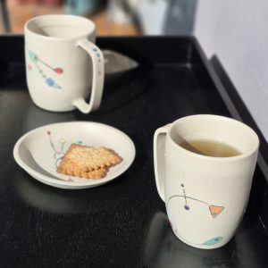 Mug en céramique artisanal avec thé et biscuit sur table en extérieur, collection Géometrik Atelier Kaolin Grenoble
