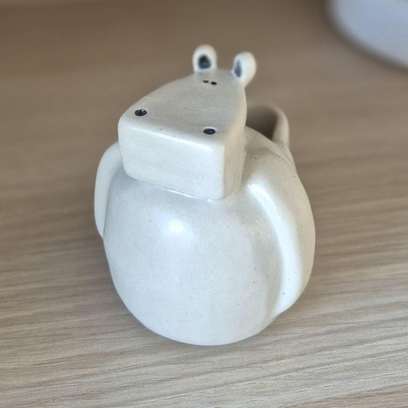 Petit vase hippopotame vide en céramique artisanale sur table en bois