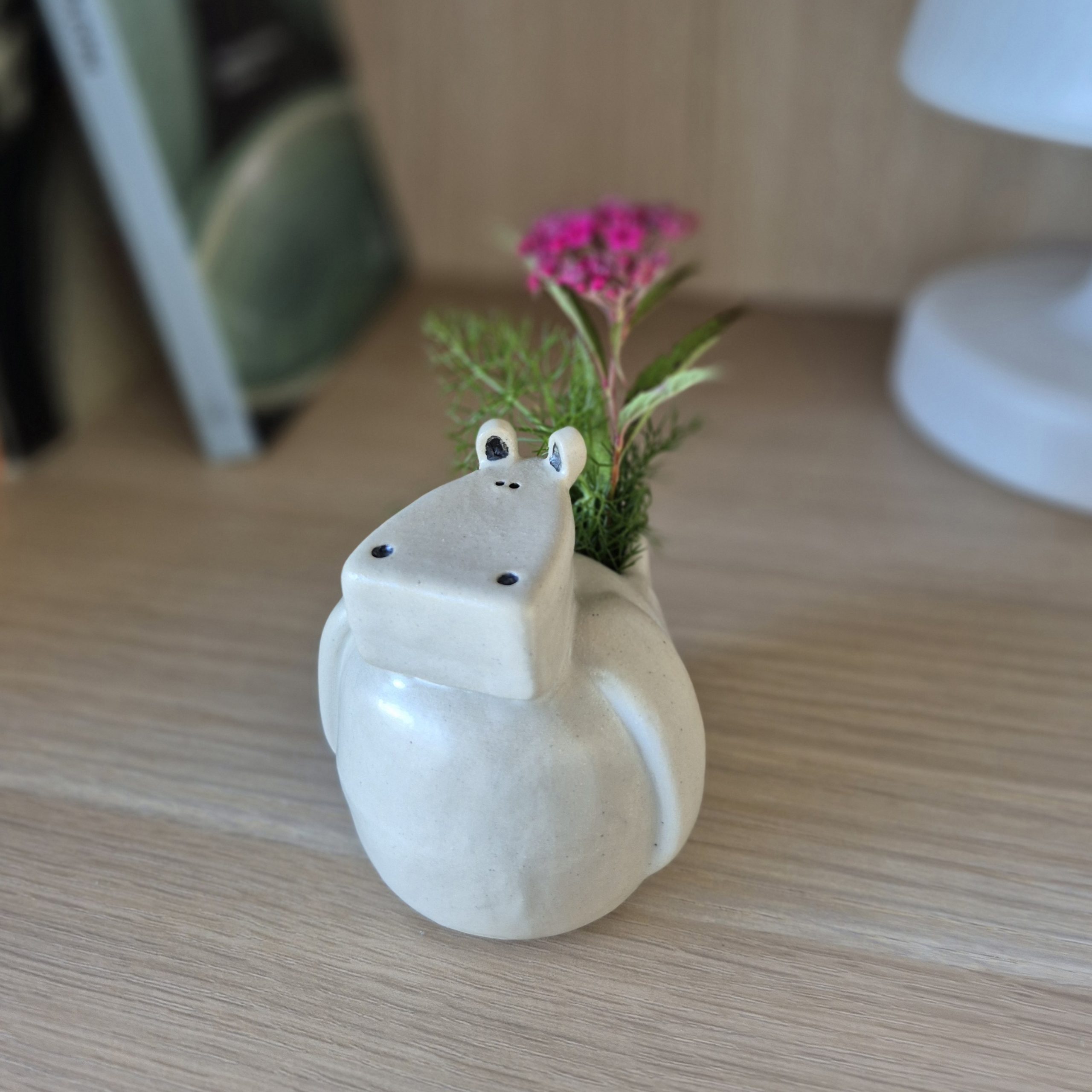 Petit vase hippopotame en céramique artisanale sur une étagère en bois