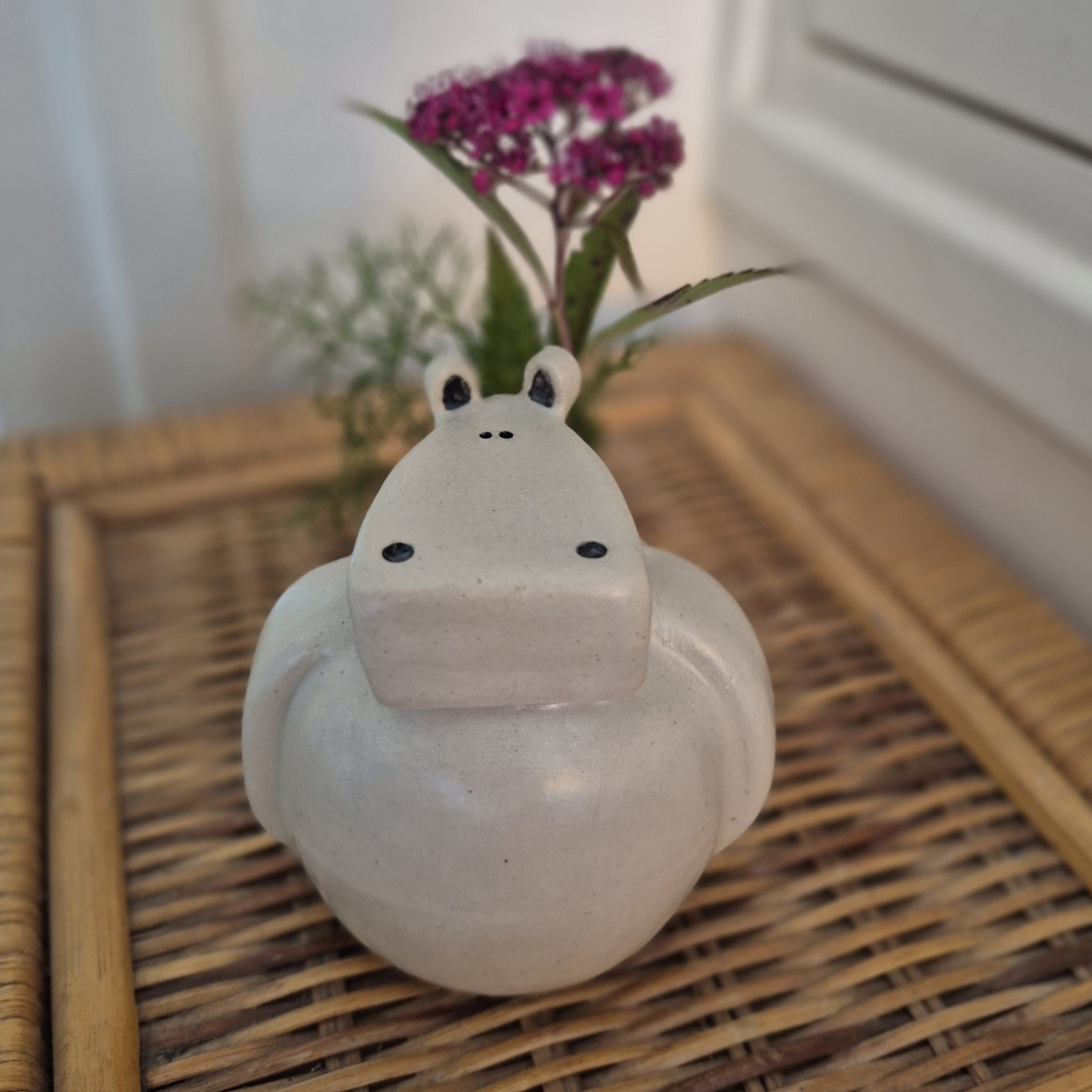Petit vase hippopotame en céramique artisanale avec fleurs sur plateau en osier