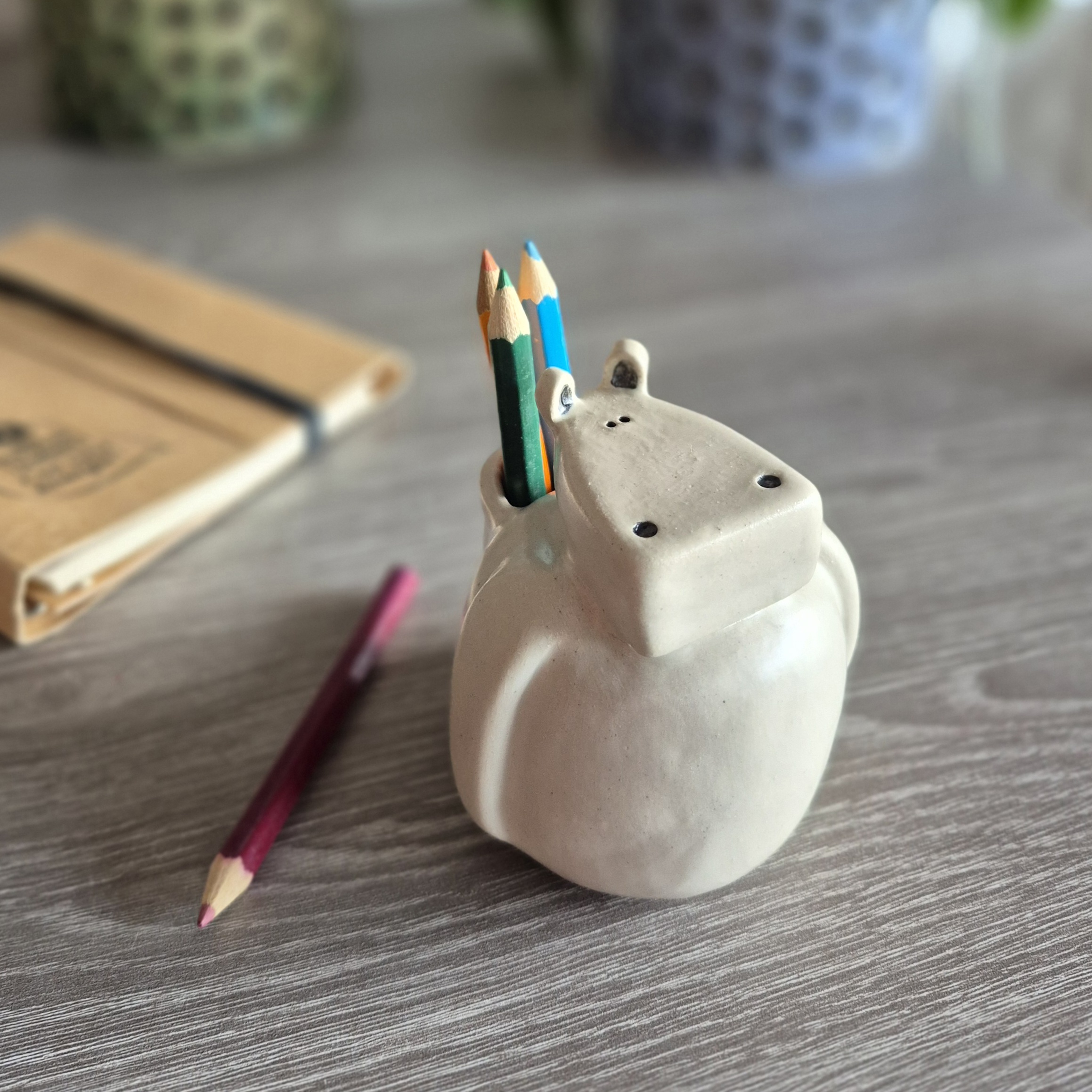 Hippopotame décoratif en céramique utilisé comme pot à crayons sur un bureau