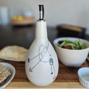 Huilier Géometrik en céramique artisanale sur une table de cuisine avec salade et huile d’olive